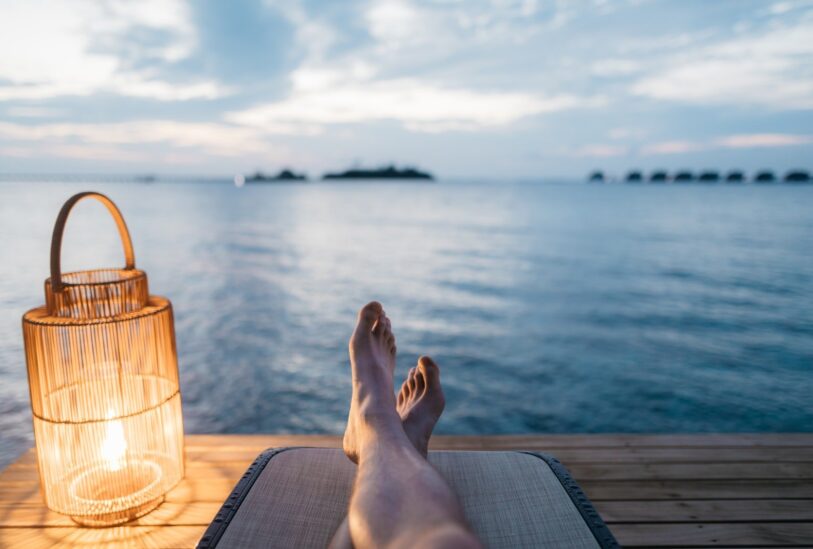 person lying on chair and facing on body of water