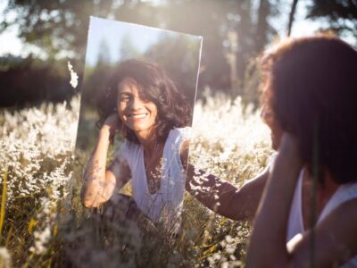 Selbstwarhrnehmung: Frau sitzt mit Spiegel im Gras
